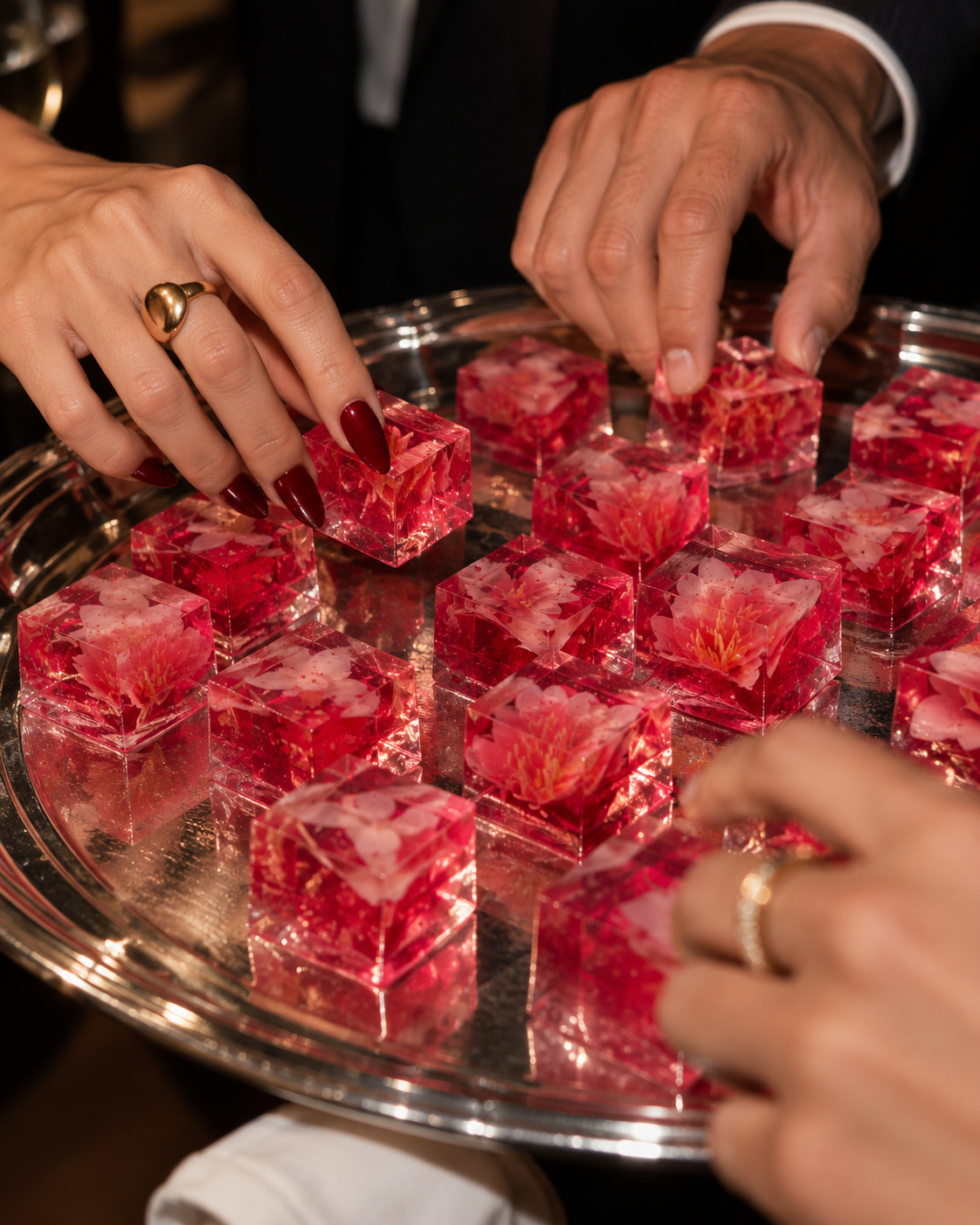 Guests reaching for pink floral Wobble Bites from a silver serving tray at an event
